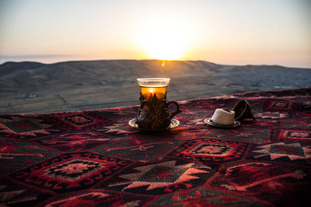 istock Eastern black tea in glass on a eastern carpet. Eastern tea concept. Armudu traditional cup. Sunset background. 1029738748