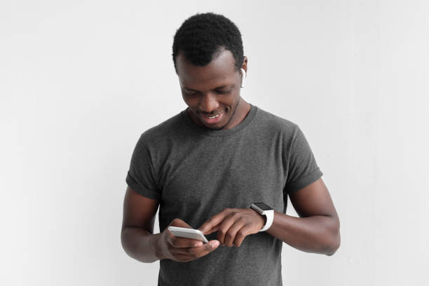 istock Young african american dark skin man looking at smartphone while texting, using mobile phone, isolated on gray background 1029750762