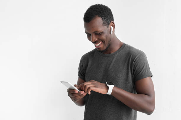 istock Young attractive african american dark skin man looking at smartphone while texting, using mobile phone, isolated on gray background 1029750778