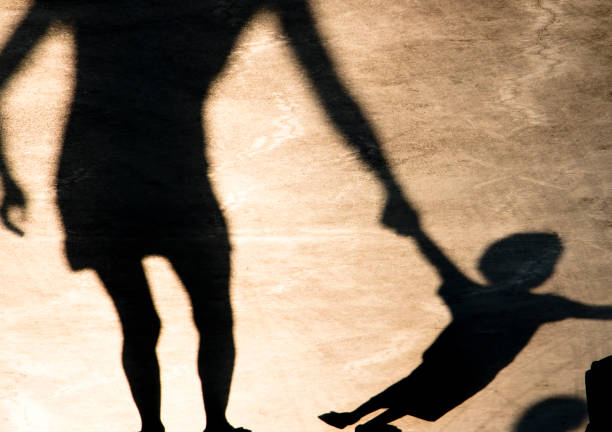 Shadows silhouettes of mother and child on summer promenade stock photo