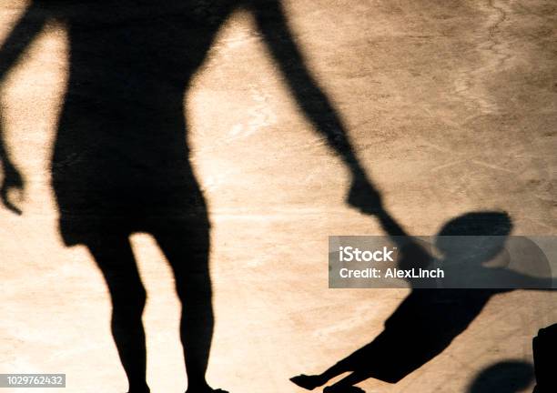 Shadows Silhouettes Of Mother And Child On Summer Promenade Stock Photo - Download Image Now