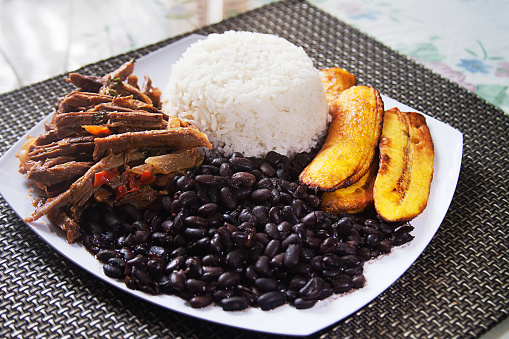 Homemade Venezuelan food. Traditional Venezuelan dish. Pabellon Criollo. White Rice, Black beans,Fried plantains, and Shredded beef
