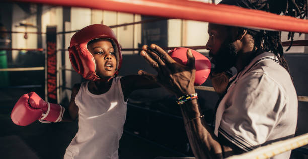 istock Kid learning boxing from his coach in a boxing ring 1029783626