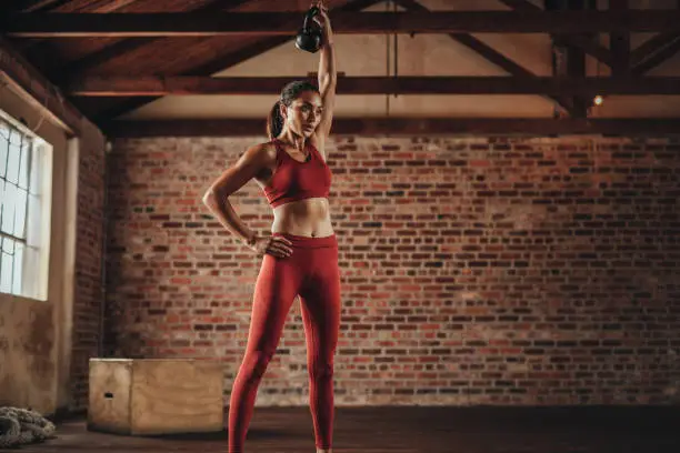 Fitness woman doing exercising with kettle bell. Determined female model doing workout with kettle bell at gym.