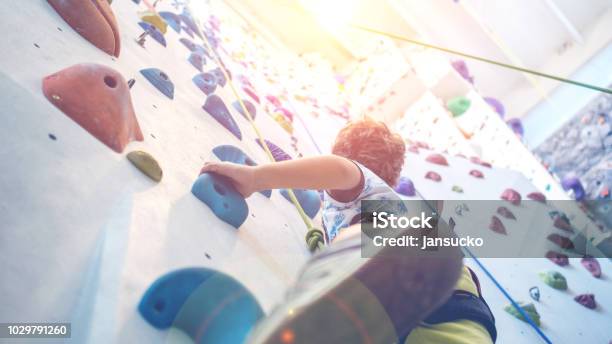 Joven Es Escalar Un Muro De Escalada Interior Foto de stock y más banco de imágenes de Escalada - Escalada, Coraje, Venciendo la adversidad