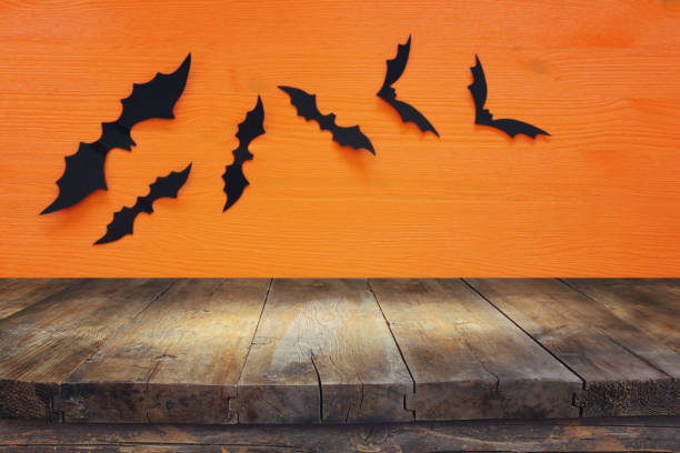 istock Halloween holiday concept. Empty rustic table in front of black bats background. Ready for product display montage. 1029794488