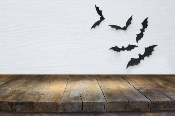 istock Halloween holiday concept. Empty rustic table in front of black bats background. Ready for product display montage. 1029794512