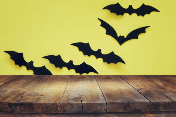 istock Halloween holiday concept. Empty rustic table in front of black bats background. Ready for product display montage. 1029794516
