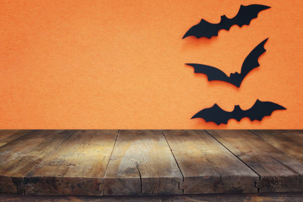 istock Halloween holiday concept. Empty rustic table in front of black bats background. Ready for product display montage. 1029794528