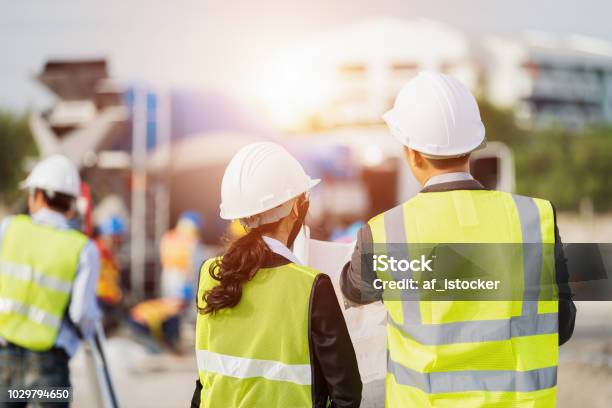 Businessman And Businesswoman Using See Plan Paper At Construction Site Stock Photo - Download Image Now