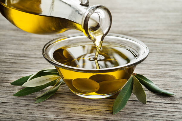 Bottle of Olive oil pouring Bottle of Olive oil pouring in a glass bowl with olives olive oil pouring antioxidant liquid stock pictures, royalty-free photos & images