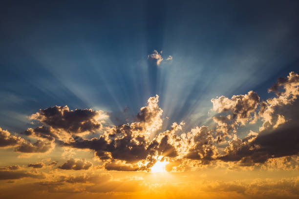 istock Blue and orange sky background with clouds and rays of sunset sun 1029811448