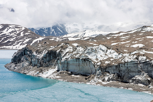 Glacier coming into Tilicho lake in Himalayas, Nepal. Mountain glacier melting into the highland lake. Melting glacier scenery.