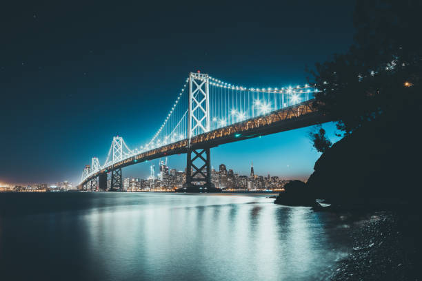 skyline de san francisco con oakland bay bridge de crepúsculo, california, usa - golden gate bridge night bridge san francisco bay fotografías e imágenes de stock