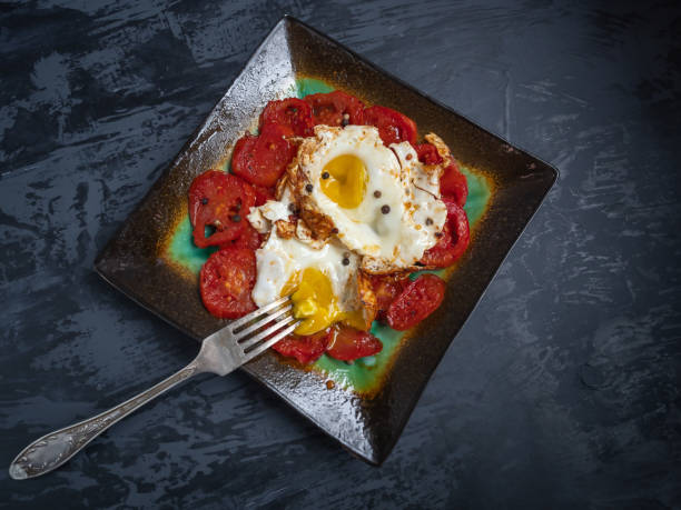 BreakfastBreakfast of fried red tomatoes and fried eggs in a ceramic decorative plate on a dark background of fried red tomatoes and fried eggs