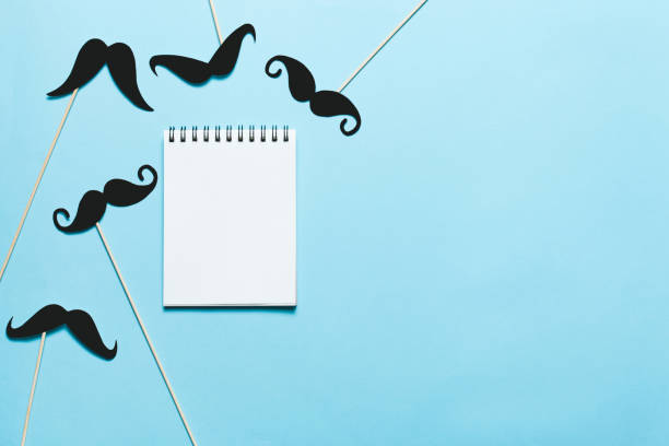 istock Many paper mustaches and a notepad on blue background. 1029838002