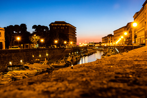 Picturesque view at sunset of the canal with boats within the city in the town Livorno, Tuscany, Italy.