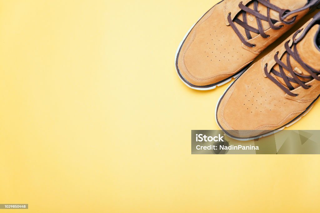 Brown boots on yellow background. Copyspace, flat lay. Top view of Brown boots on yellow background. Copyspace, flat lay. Traveling boots, minimalist. Adventure Stock Photo