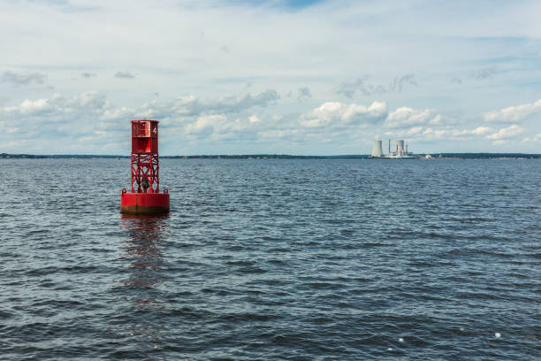 In the foreground a floating red buoy; in the background, a shutdown power station (MA, USA)
