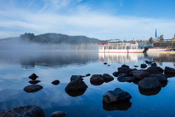 titisee nella foresta nera con nave nella nebbia al cielo blu - black forest forest sky blue foto e immagini stock