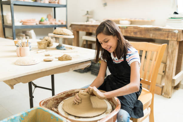 Girl Pursuing Hobby Of Pottery In Class Happy preteen girl pursuing hobby of pottery while sitting in class pottery making stock pictures, royalty-free photos & images