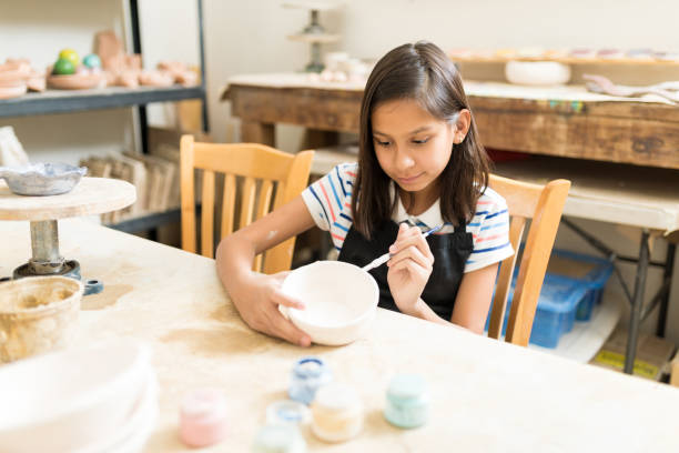 istock Pottery Student Painting Bowl With Brush At Table 1029864660