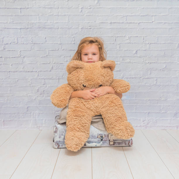 istock girl, child with suitcase on white brick wall background 1029873566