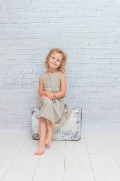 istock girl, child with suitcase on white brick wall background 1029873992