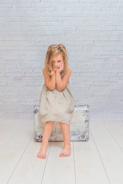 istock girl, child with suitcase on white brick wall background 1029874034