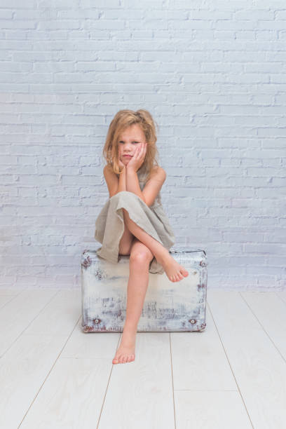 istock girl, child with suitcase on white brick wall background 1029874070