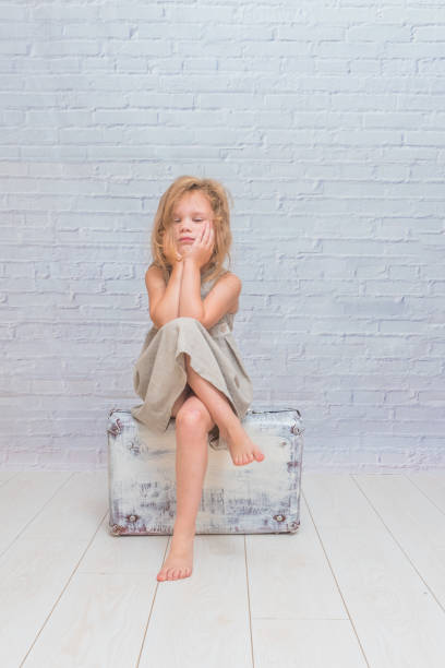 istock girl, child with suitcase on white brick wall background 1029874078