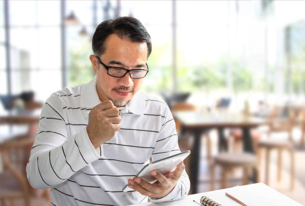 bel homme assis dans le café et l’écriture sur une tablette numérique. beaucoup de gens est capables d’étudier ou de travailler dans des endroits différents en raison de la communication avec internet. - male5 photos et images de collection