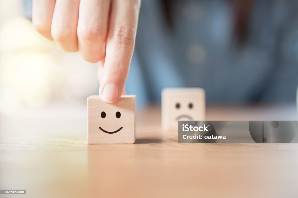 Nahaufnahme der Hand wählen Sie Smiley-Gesicht und unscharfen Bedrücktes Gesichtssymbol auf Holz Würfel - Lizenzfrei Positive Emotionen Stock-Foto