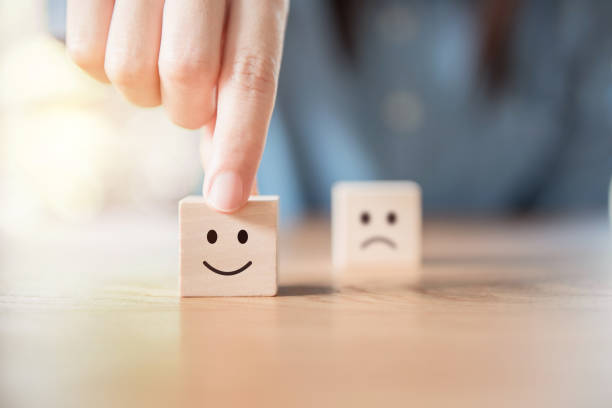 Close up hand choose smiley face and blurred sad face icon on wood cube Close up costomer hand choose smiley face and blurred sad face icon on wood cube, Service rating, satisfaction concept. positive emotion stock pictures, royalty-free photos & images