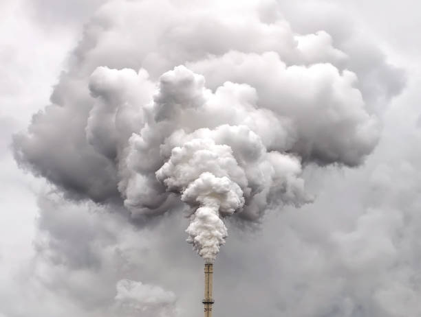 fumo dal tubo di fabbrica contro il cielo nuvoloso scuro - gas di scarico foto e immagini stock