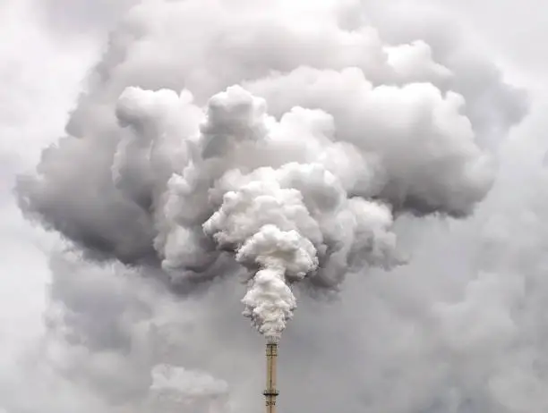 Photo of Smoke from factory pipe against dark overcast sky