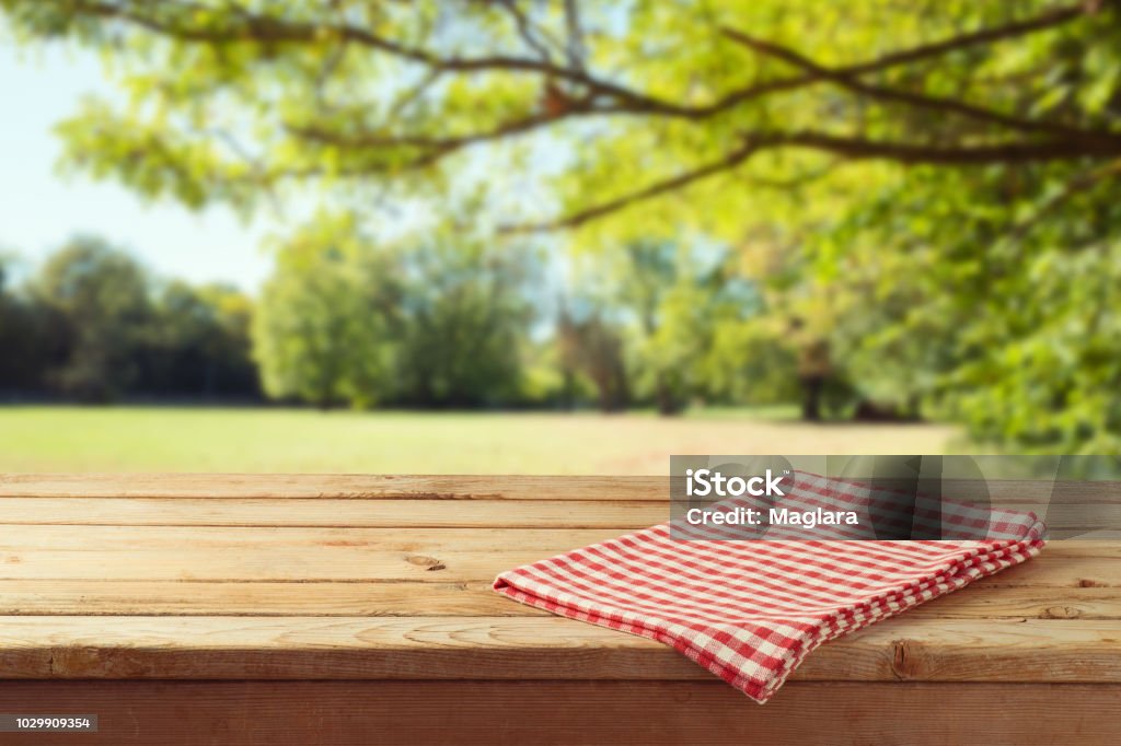 Empty wooden table with tablecloth over autumn nature park background Table Stock Photo