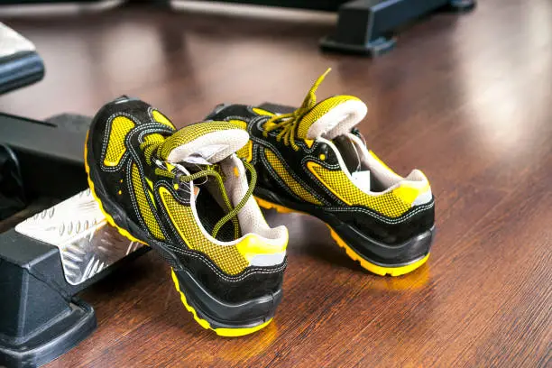 Unbranded modern sneaker in the gym. Black-Yellow. Comfortable shoes. Wearing sport shoes, doing wide step, demonstrating healthy way of life, wide shot. copy space for text.