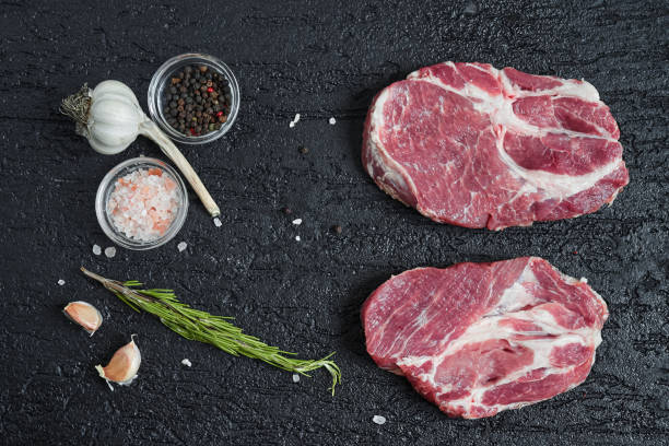 istock Fresh raw boneless pork neck slices on black stone background. 1029922328