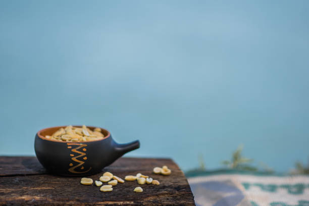 хрустящий, жареный и соленый арахис, очищенный. питательная закуска в небольшом керимическом горшке на фоне натурального коричневого дере� - 2655 стоковые фото и изображения