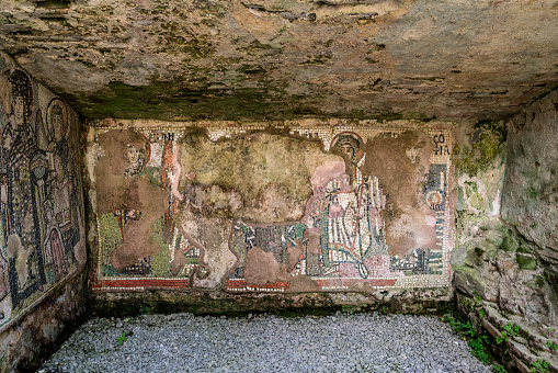 Flaking mosaic figures on a wet ancient roman cave wall. Horizontal composition taken at a open Amphitheater in the city Durres Albania Eastern Europe.