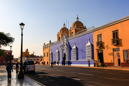 Trujillo, Peru, July 2018: Colored buildings next to the cathedral, in the city's main square, bathed in the light of sunset