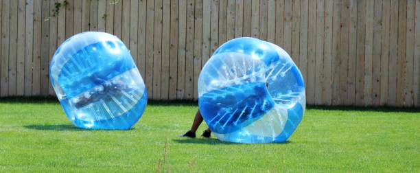 Two kids roll inside giant plastic balls Two kids roll inside giant plastic balls zorb ball stock pictures, royalty-free photos & images