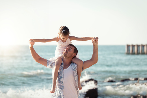 Father and daughter having fun on the beach. Playing together outdoors on a summer