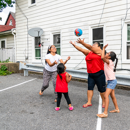 El gran Latino feliz, familia Mexico-Americana - la mujer alegre positivo de cuerpo, madre y los niños, las niñas de diferentes edades - jugando con una pelota al aire libre photo