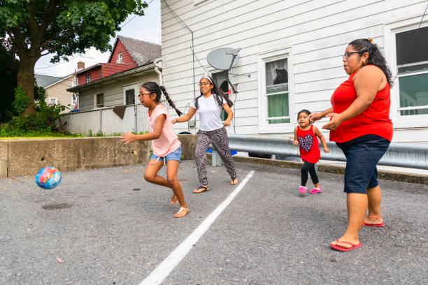 la grande felice famiglia latino-americana - la madre, la donna allegra positiva al corpo e i bambini, ragazze di diverse età - che giocano con una palla all'aperto - family american culture mother child foto e immagini stock