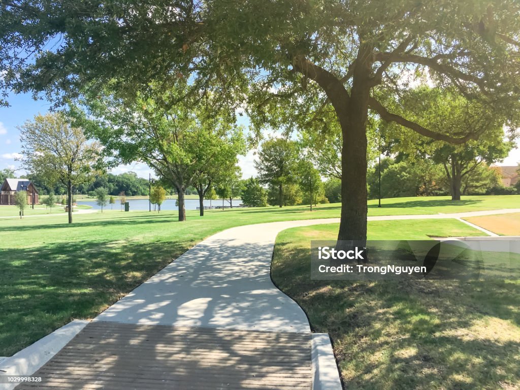 Green park with pathway from shady parking lots in Coppell, Texas, USA Lakeside park with pathway trail system in Coppell, Texas, USA. View from shady parking lot Texas Stock Photo
