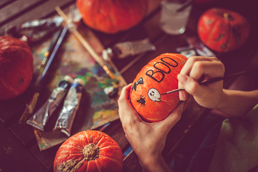 Woman painting on pumpkin preparing to Halloween in autumn