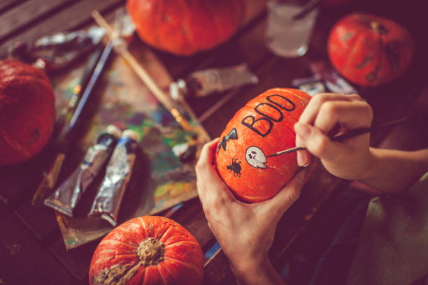 Young girl painting on pumpkin in Halloween stock photo