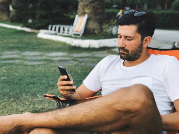 istock Young man working on mobile phone in a garden 1030007316